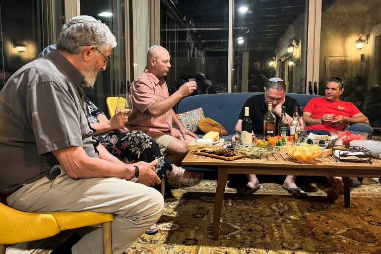 David (C), un israelí cuyo hijo combate en Gaza, comparte con amigos en su casa en la ciudad norteña de Tiberíades, el 13 de junio de 2024 (Antone BOYER)