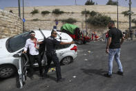 Un agente de la policía israelí protege a un conductor judío atacado por manifestantes palestinos cerca de la zona antigua de Jerusalén, el lunes 10 de mayo de 2021. La policía chocó el lunes con manifestantes palestinos en un disputado lugar de culto en Jerusalén. (AP Foto/Ohad Zwigenberg)