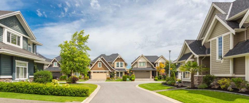 Nicely trimmed and manicured garden in front of a luxury house on a sunny summer day. Street of houses in the suburbs of Canada.