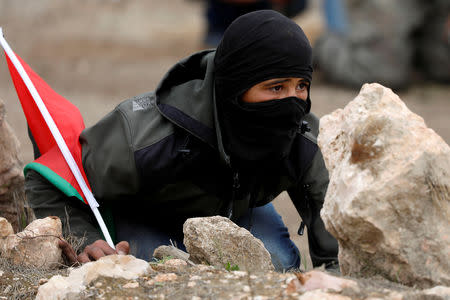 A Palestinian demonstrator takes cover during clashes with Israeli troops at a protest marking the Land Day in al-Mughayer village, in the Israeli-occupied West Bank March 29, 2019. REUTERS/Mohamad Torokman