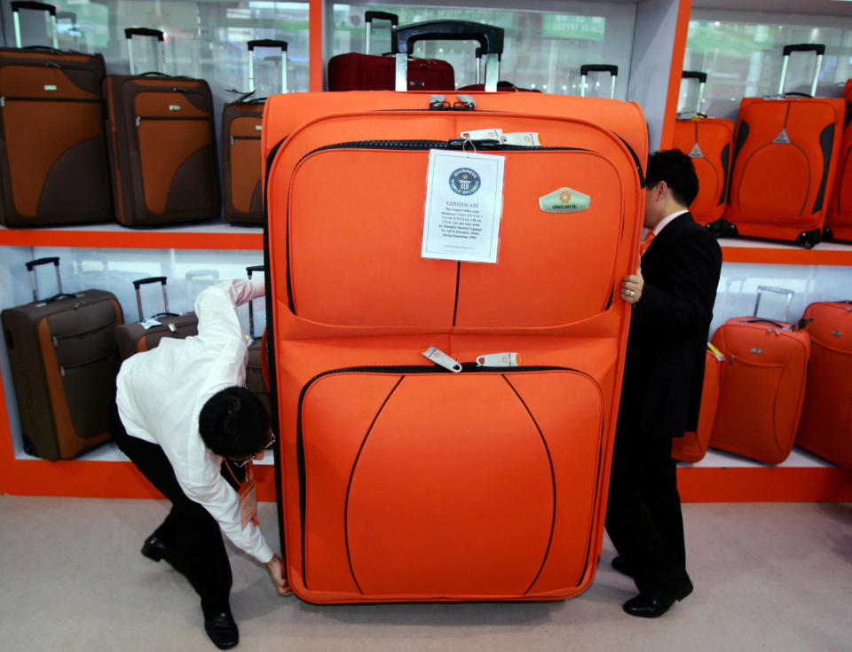 Staff members try to move a huge trolley case during the 100th Chinese Export Commodities Fair in Guangzhou, south China's Guangdong province October 15, 2006. This trolley case has been certified as the world's largest by the Guinness World Records and measures 175cm (5ft 9in) by 115cm (3ft 9.3in) by 46cm (1ft 6.1in) thick. REUTERS/Alvin Chan