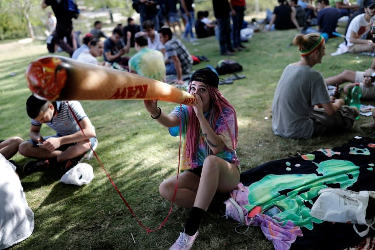 An Israeli girl poses with a mock marijuana joint in Jerusalem on April 20, 2017 during a rally to express defiance of current laws