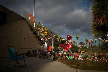 An empty chair is seen in front of flowers and mementoes placed on a fence to commemorate the victims of the mass shooting at Marjory Stoneman Douglas High School, in Parkland, Florida, U.S., February 20, 2018. REUTERS/Carlos Garcia Rawlins