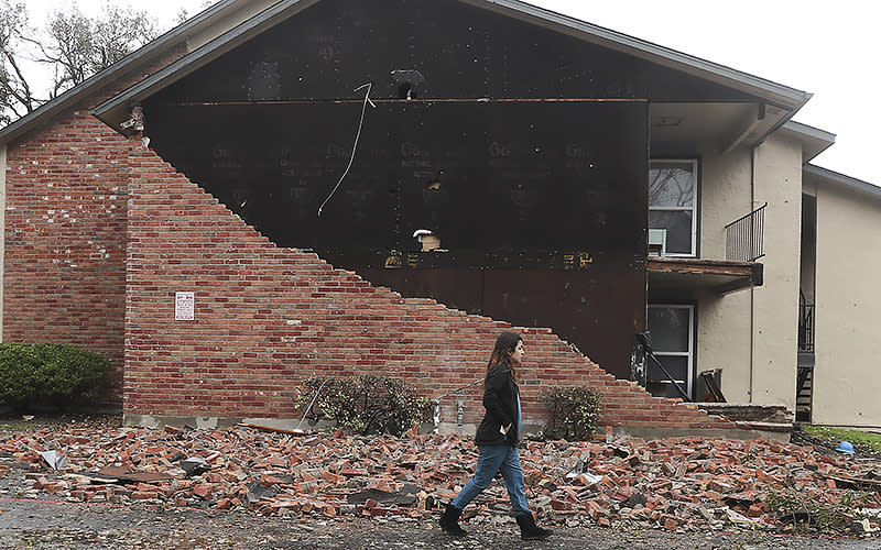 A resident walks past an apartment unit where the bricks fell off at Deer Park Apartments after a powerful storm system came through the area on Jan. 24 in Deer Park, Texas. <em>Elizabeth Conley/Houston Chronicle via AP</em>