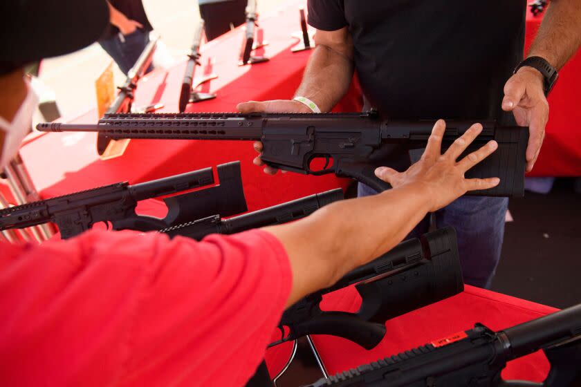 A clerk shows a customer a TPM Arms LLC California-legal featureless AR-10 style .308 rifle displayed for sale at the company's booth at the Crossroads of the West Gun Show at the Orange County Fairgrounds on June 5, 2021 in Costa Mesa, California. - Gun sales increased in the US following Covid-19 pandemic lockdowns. On June 4, a San Diego federal court judge overturned California's three-decade old ban on assault weapons, defined as a semiautomatic rifle or pistol with a detachable magazine and certain features, but granted a 30-day stay for a State appeal and likely future court decisions on the constitutionality of the ban under the Second Amendment. An industry of California legal 