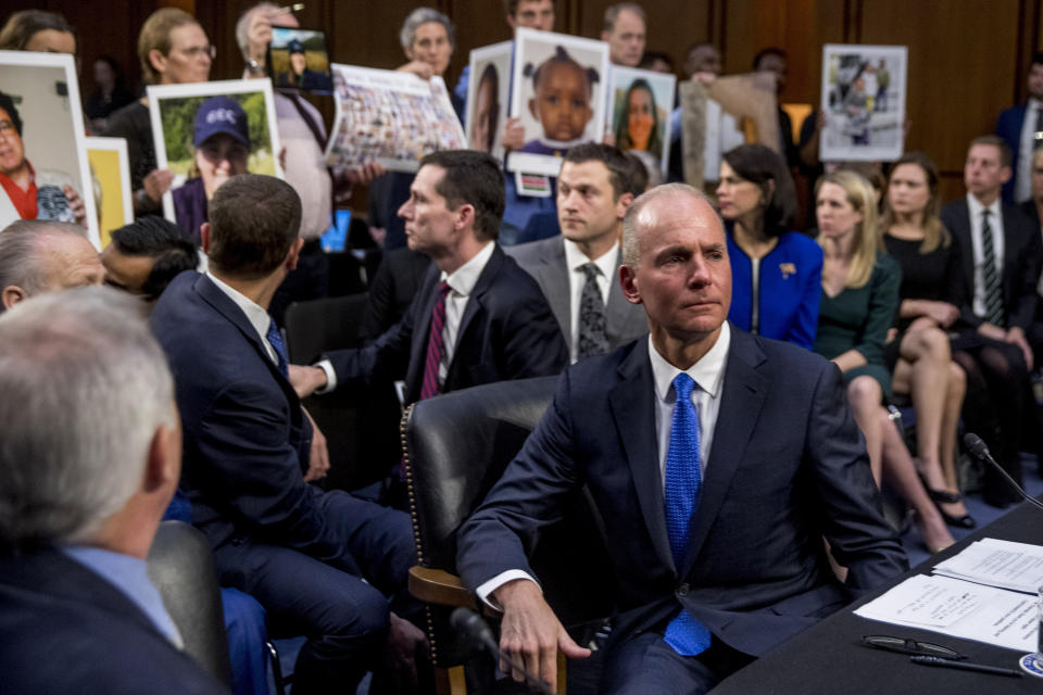 Boeing Company President and Chief Executive Officer Dennis Muilenburg, right foreground, watches as family members hold up photographs of those killed in the Ethiopian Airlines Flight 302 and Lion Air Flight 610 crashes during a Senate Transportation Committee hearing on 'Aviation Safety and the Future of Boeing's 737 MAX' on Capitol Hill in Washington, Tuesday, Oct. 29, 2019. (AP Photo/Andrew Harnik)