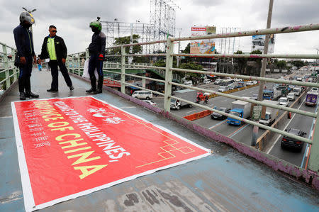 Traffic enforcers stand next to a banner reading "Welcome to the Philippines, Province of China" after removing it from an overpass along the C5 road intersection in Taguig, Metro Manila, Philippines July 12, 2018. REUTERS/Erik De Castro