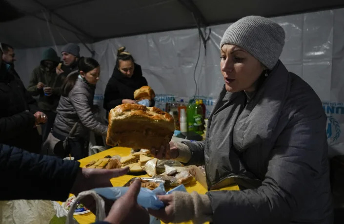 A volunteer gives free meal to people who lost electrical power after recent Russian rocket attack in a heating point in the town of Vyshhorod, north of Kyiv, Ukraine, Friday, Nov. 25, 2022. (AP Photo/Efrem Lukatsky)