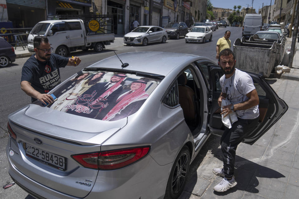 A printing specialist laminates a Jordanian vehicle with pictures of, from right, King Abdullah II, Crown Prince Hussein, Saudi architect Rajwa Alseif and Queen Rania, in the capital Amman, Jordan, Wednesday, May 31, 2023. Crown Prince Hussein and Saudi architect Rajwa Alseif are to be married on Thursday at a palace wedding in Jordan, a Western-allied monarchy that has been a bastion of stability for decades as Middle East turmoil has lapped at its borders. (AP Photo/Nasser Nasser)