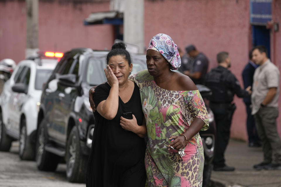 Silvia Palmieri, who is the mother of a teacher who survived a stabbing attack at the Thomazia Montoro school, left, leaves the school comforted by a friend in Sao Paulo, Brazil, Monday, March 27, 2023. A 13-year-old student fatally stabbed a 71-year-old teacher and wounded three teachers and two fellow students Monday in a knife attack at the public school, state officials said. (AP Photo/Andre Penner)