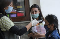 A medical staff checks the temperature of a girl at the entrance of Oking Hospital in Kohima, capital of the northeastern Indian state of Nagaland, Monday, April 13, 2020. A man from Nagaland state has tested positive for COVID- 19, becoming the first case from the state. The new coronavirus causes mild or moderate symptoms for most people, but for some, especially older adults and people with existing health problems, it can cause more severe illness or death. (AP Photo/Yirmiyan Arthur)