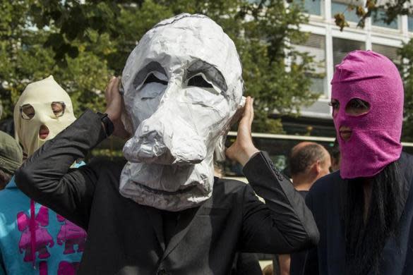 People wear a caricature mask of Russian President Vladimir Putin (R) and trademark Pussy Riot balaclavas during a support rally for the detained Moscow based feminist punk band outside the Russian embassy in Berlin, August 17, 2012.