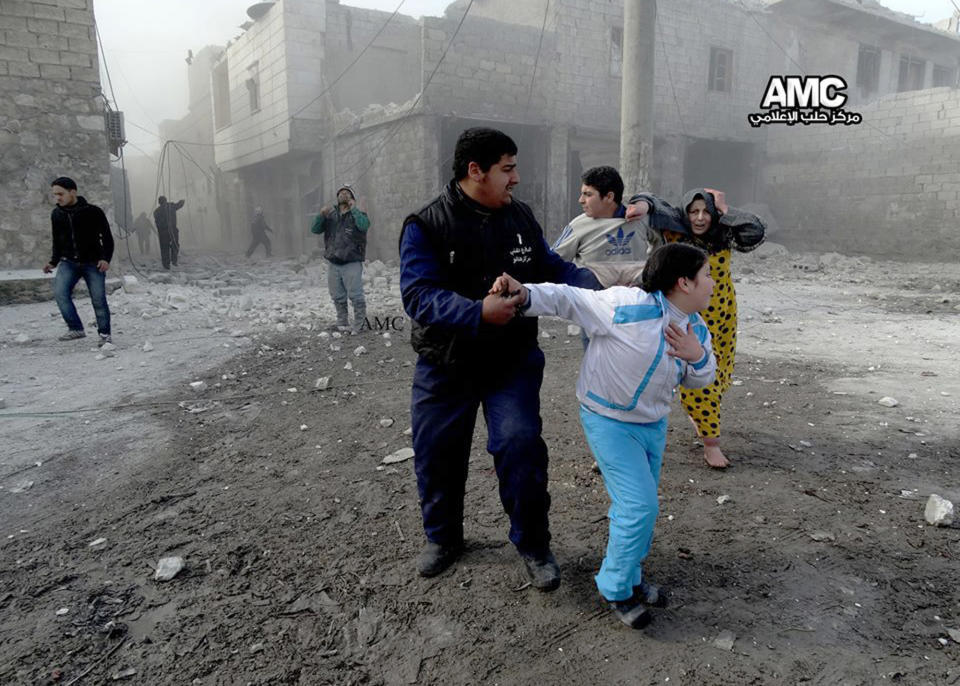 In this picture taken on Friday Jan. 31, 2014, a citizen journalism image provided by Aleppo Media Center (AMC), an anti-Bashar Assad activist group, and authenticated based on its contents and other AP reporting, Syrian family members run in the street following an attack by a Syrian government forces warplane, in Aleppo, Syria. Syrian military helicopters dropped barrels packed with explosives on rebel-held areas of the northern city of Aleppo on Saturday, killing at least a dozen of people including a family trapped in a car, as government forces inched closer to opposition-held areas. (AP Photo/Aleppo Media Center, AMC)