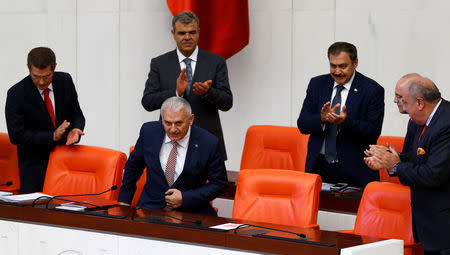 Turkey's new Prime Minister Binali Yildirim is applauded by his ministers as he arrives to read his government's programme at the Turkish parliament in Ankara, Turkey, May 24, 2016. REUTERS/Umit Bektas