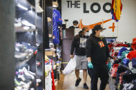 Roni Colvert, center, makes a purchase after selecting her goods through the front door from curb-side at The Loop fashion and shoe store as businesses slowly begin to reopen after social distancing restrictions shuttered storefronts nationwide, Tuesday, May 26, 2020, in Yonkers, N.Y. (AP Photo/John Minchillo)