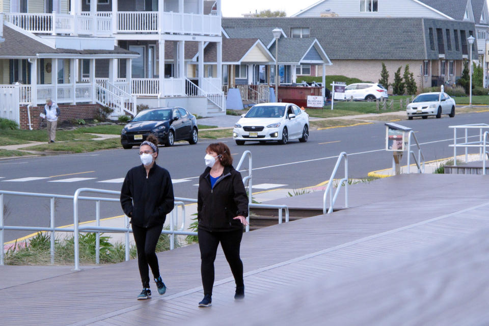 In this Tuesday, May 12, 2020 photo, people walking on the boardwalk in Belmar, N.J. as the town prepared for the summer season amid the coronavirus pandemic. Gov. Phil Murphy is expected to issue guidelines on Thursday, May 14, 2020, on when and how New Jersey's beaches can begin to reopen during the COVID-19 pandemic. (AP Photo/Wayne Parry)