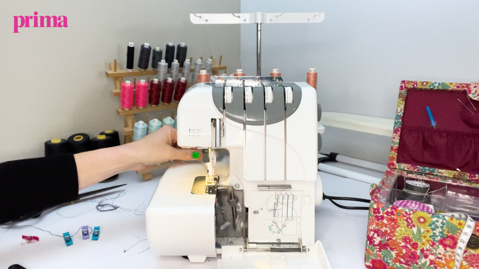 hands threading an overlocker sewing machine