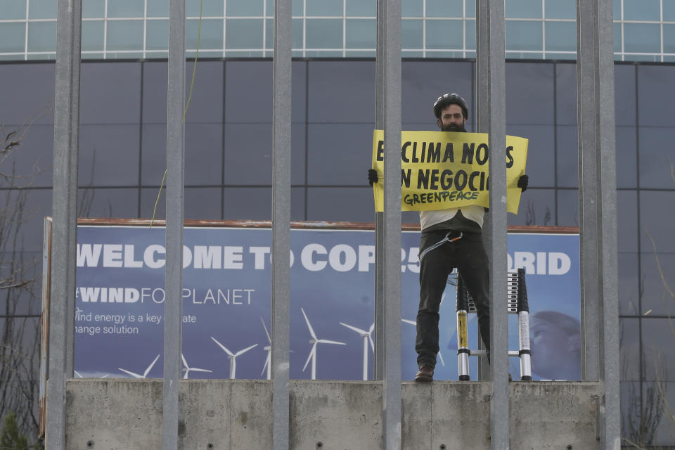A Greenpeace activist displays a banner reading 'The climate is not a business' outside the COP25 climate talks congress in Madrid, Spain, Friday, Dec. 13, 2019. The United Nations Secretary-General has warned that failure to tackle global warming could result in economic disaster. (AP Photo/Paul White)