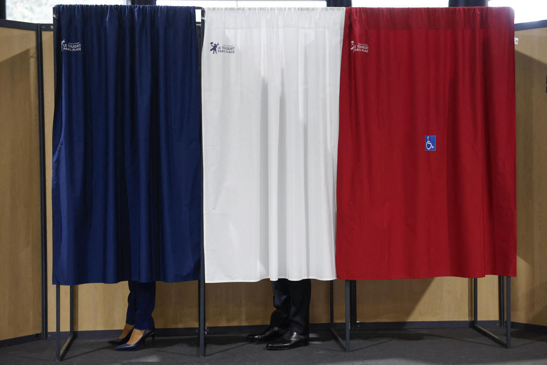 French President Emmanuel Macron (C) and French First Lady Brigitte Macron (L) vote at a polling station in the second round of French parliamentary elections in Le Touquet-Paris-Plage, France, 07 July 2024. MOHAMMED BADRA/Pool via REUTERS