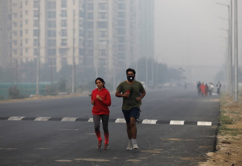 People jog on a foggy morning in Noida on the outskirts of New Delhi