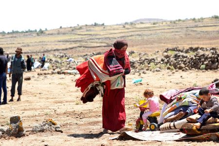 Internally displaced woman from Deraa province holds blankets near the Israeli-occupied Golan Heights, in Quneitra, Syria June 21, 2018. REUTERS/Alaa al-Faqir