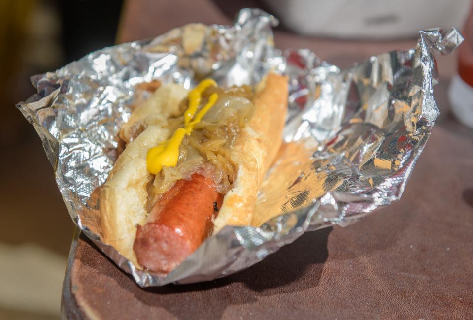 A sausage covered in onions and mustard is ready for eating at the Butch's Place food cart in downtown Peoria.
