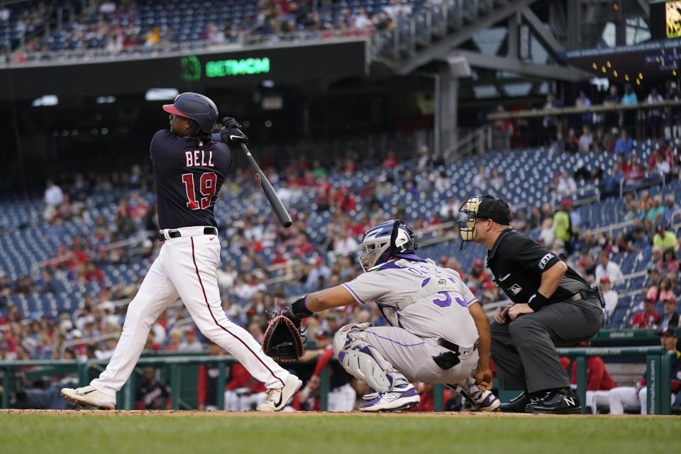 Washington Nationals' Josh Bell, left, doubles in front of Colorado Rockies catcher Elias Diaz and home plate umpire Sean Barber in the first inning of a baseball game, Thursday, May 26, 2022, in Washington. Keibert Ruiz scored on the play. (AP Photo/Patrick Semansky)