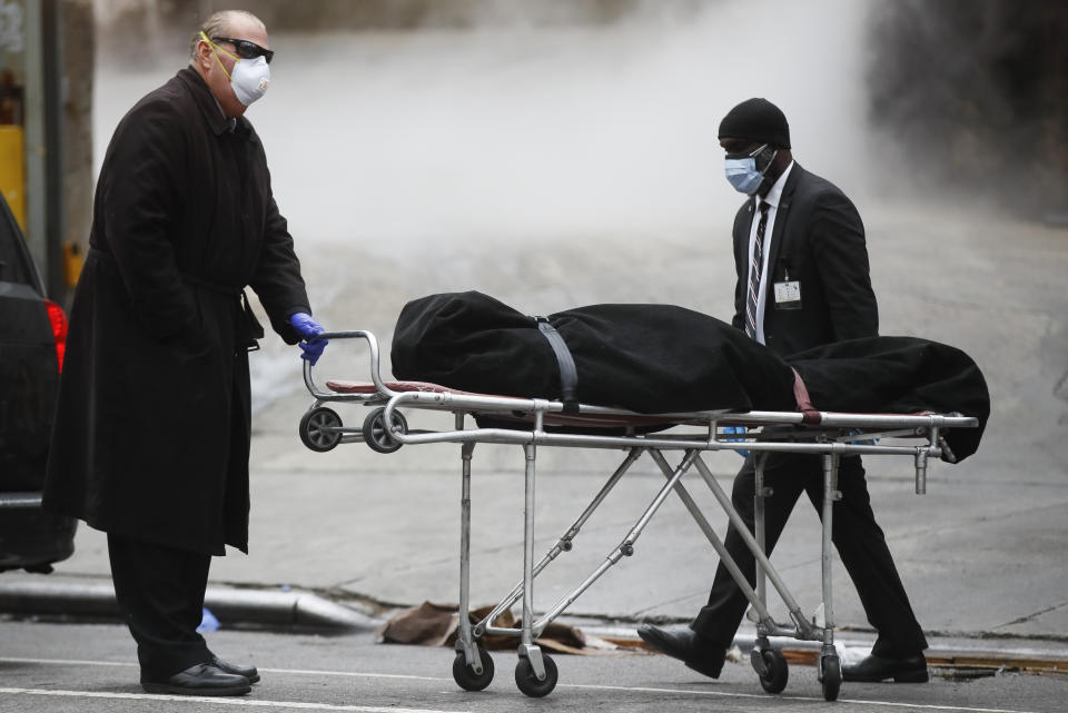 A funeral director wears personal protective equipment due to COVID-19 concerns while collecting a body at The Brooklyn Hospital Center, Thursday, April 9, 2020, in the Brooklyn borough of New York. New York state posted a record-breaking number of coronavirus deaths for a third consecutive day even as a surge of patients in overwhelmed hospitals slowed, while isolation-weary residents were warned Thursday the crisis was far from over. (AP Photo/John Minchillo)