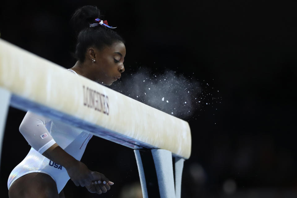 Simone Biles of the United States blows the chalk from the balance beam before performing in the women's all-around final at the Gymnastics World Championships in Stuttgart, Germany, Thursday, Oct. 10, 2019. (AP Photo/Matthias Schrader)