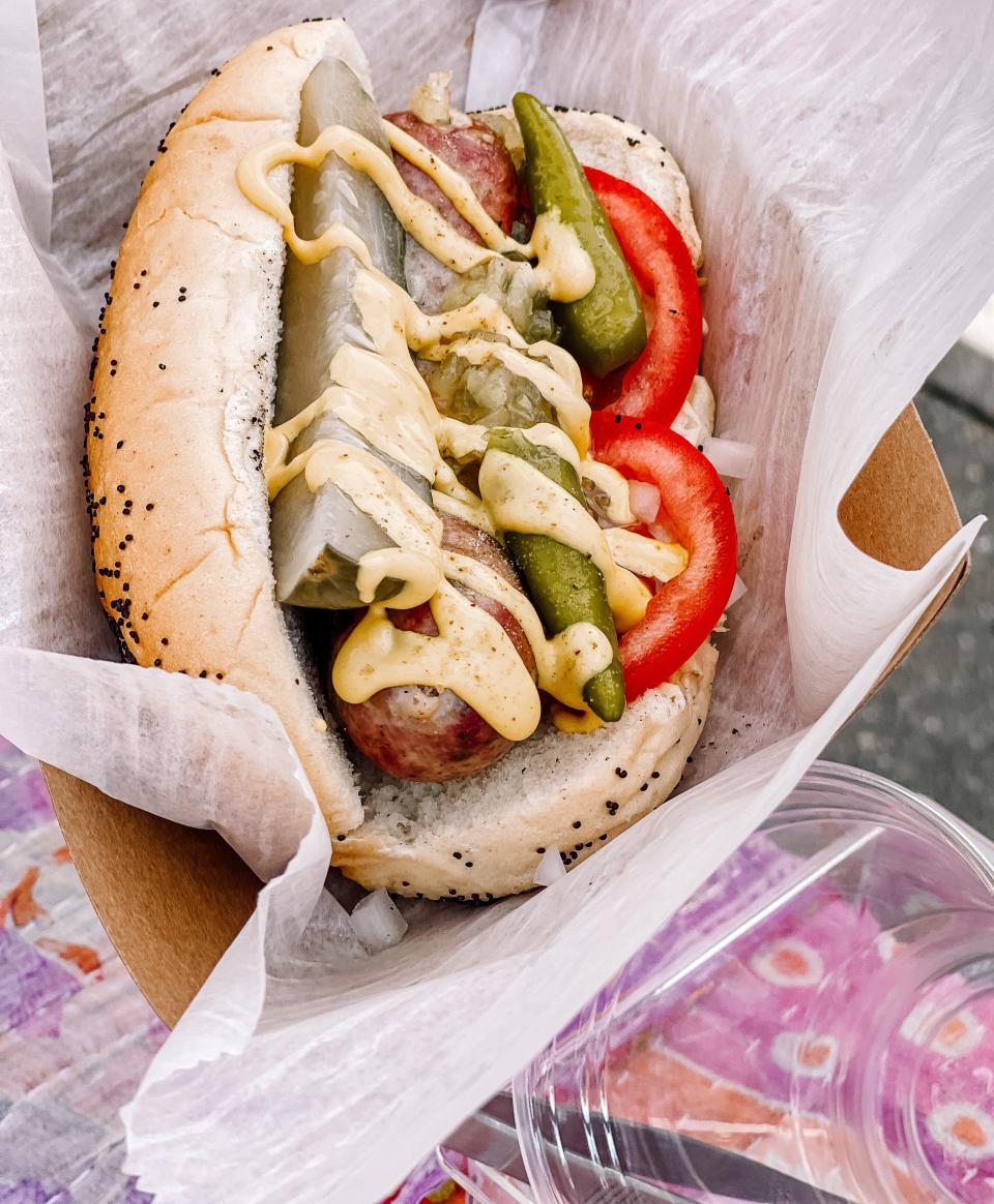 Stolen Streetlights’ Chicago Dog at the Market Square Farmers Market on June 15, 2022. The sausage is topped with sport peppers, house pickles, relish, chopped onion, tomato, yellow mustard, and celery salt on a poppyseed bun.