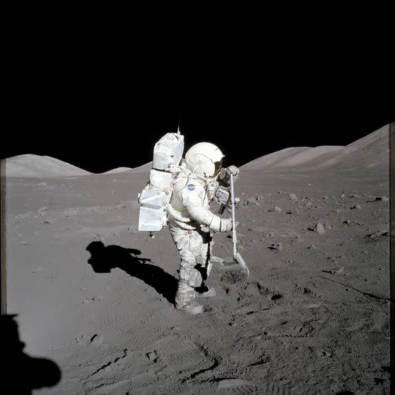 Astronaut Harrison Schmitt uses a lunar rake to collect lunar soil.