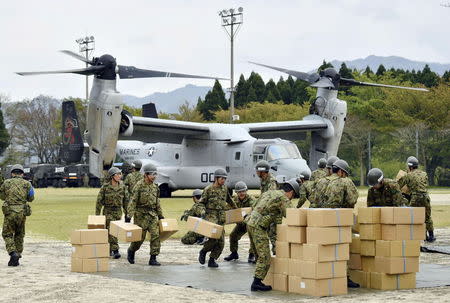 Japan Ground Self-Defense Force soldiers carry aid materials from a U.S. military Osprey aircraft (behind them) after a series of earthquakes, at Hakusui sports park in Minamiaso town, Kumamoto prefecture, southern Japan, in this photo taken by Kyodo April 18, 2016. Mandatory credit REUTERS/Kyodo