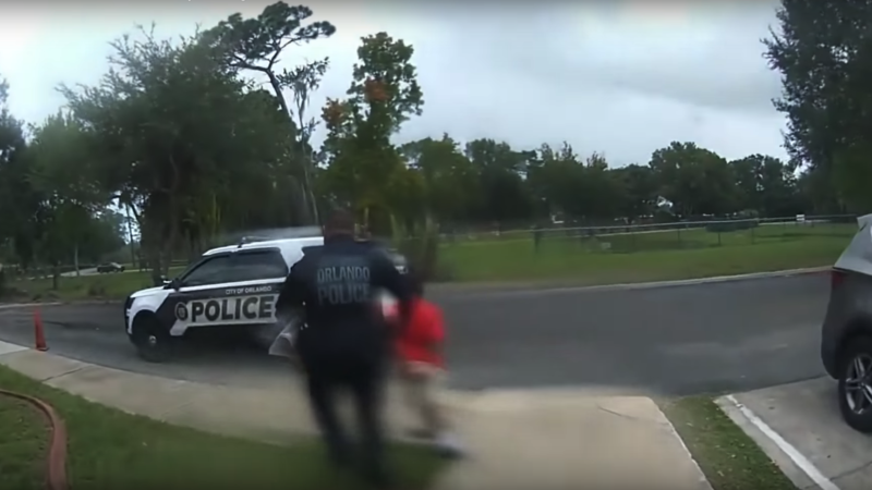 police officer leading a small child away in handcuffs