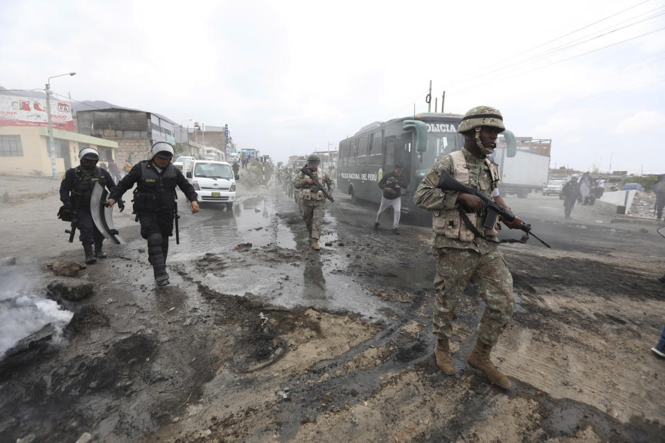 Soldiers and police prepare to clear the highway of debris placed by supporters of ousted Peruvian President Pedro Castillo protesting his detention in Arequipa, Peru, Thursday, Dec. 15, 2022. Peru's new government declared a 30-day national emergency on Wednesday amid violent protests following Castillo's ouster, suspending the rights of "personal security and freedom" across the Andean nation. (AP Photo/Fredy Salcedo)