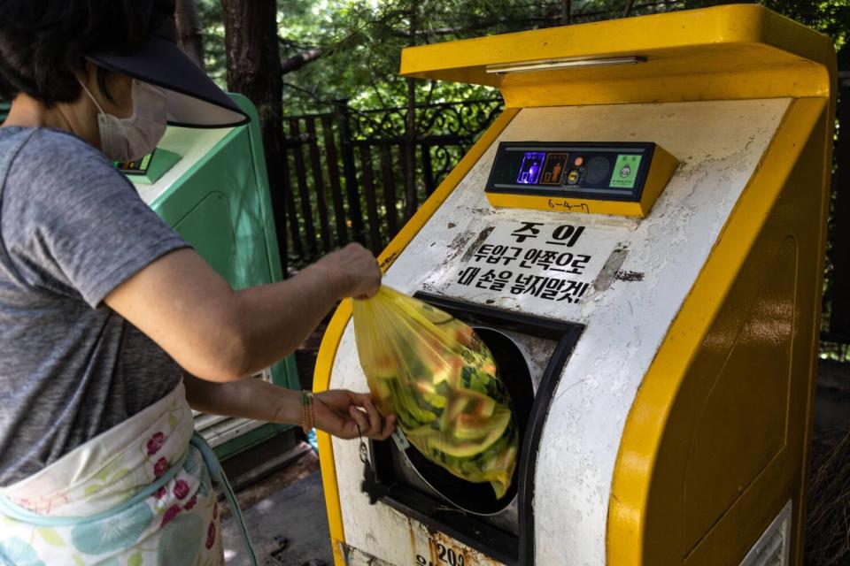 A woman deposits the food waste into a food collecting machine called "CleanNet"