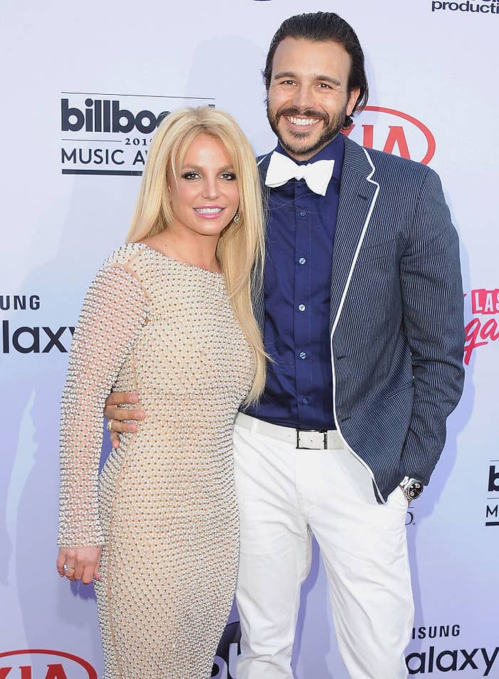 Britney and Charlie pose together at an event; she wears a mesh dress and he's in a striped blazer and bow tie