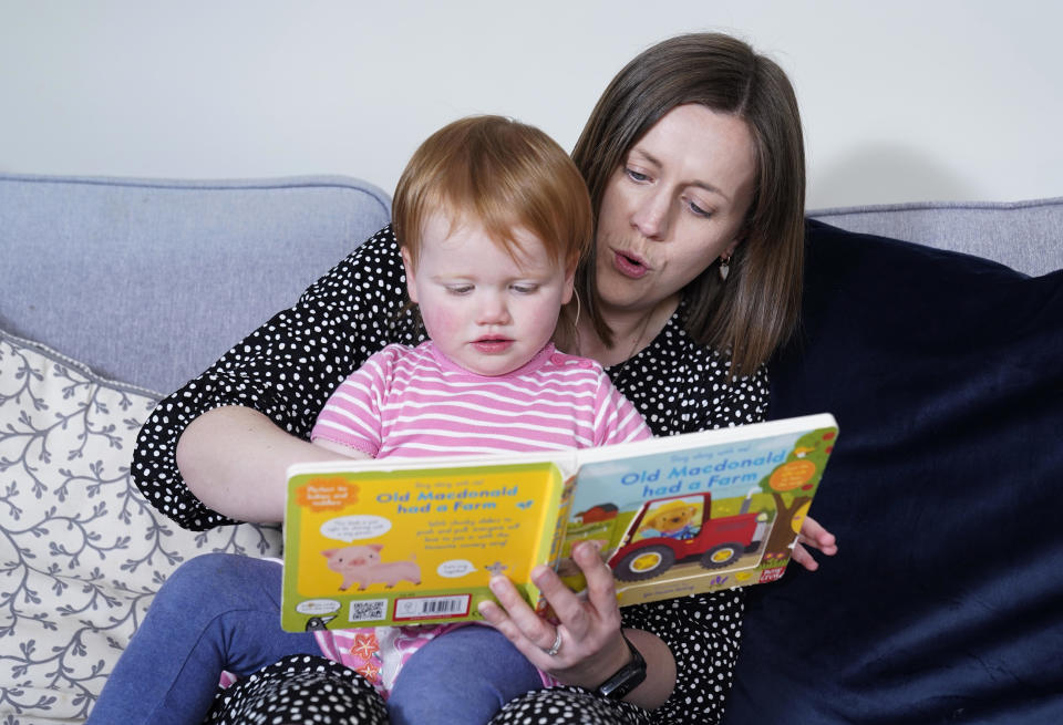 Opal Sandy, who was born completely deaf due to a rare genetic condition but can now hear unaided for the first time after receiving ground-breaking gene therapy at 11-months-old, reads with her mother Jo at their home in Eynsham, England, May 7, 2024. / Credit: Andrew Matthews/PA Images/Getty