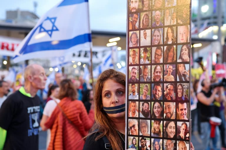A protester with a zip over her mouth holds up photographs of the Israeli hostages at a Tel Aviv rally demanding that the government strike a deal with Hamas for their release (JACK GUEZ)