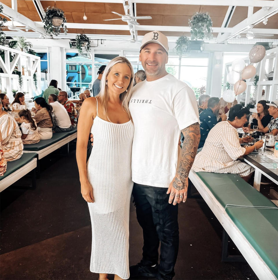 Shawn Dell, who is battling a flesh-eating bacteria, and his wife Kat dressed in white, standing in a restaurant. 