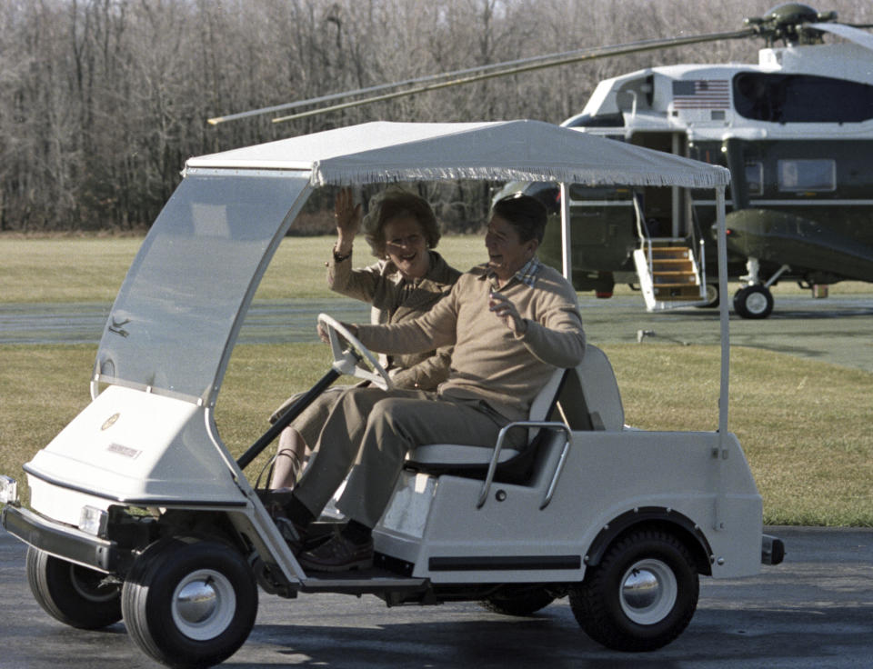 FILE - President Ronald Reagan drives British Prime Minister Margaret Thatcher in a golf cart after her arrival for a private visit at Camp David, Md., Dec. 22, 1984. (AP Photo/Ron Edmonds, File)