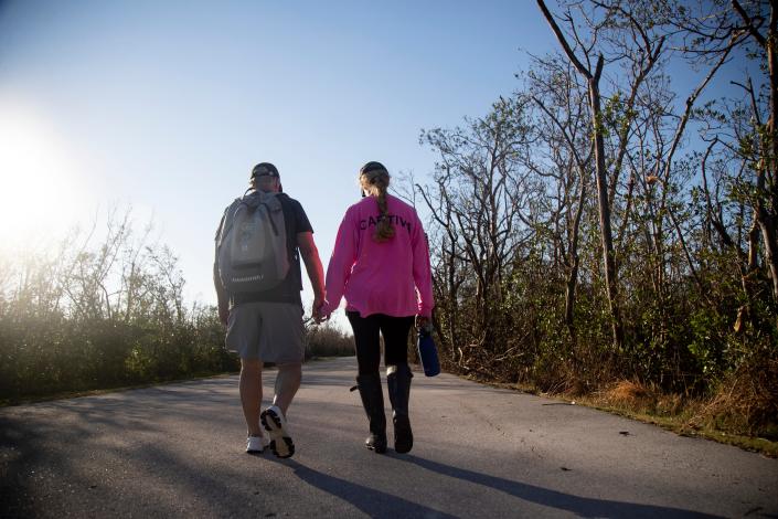 Roger and Sheila Baker walk down the street from a boat dock on the way to visit their house on Sanibel on Friday, Oct. 7, 2022. They were able to grab some of their clothes and take photos of their home, which was damaged by Hurricane Ian.