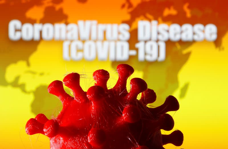 A 3D-printed coronavirus model is seen in front of a world map and the words "CoronaVirus Disease (Covid-19)" on display in this illustration