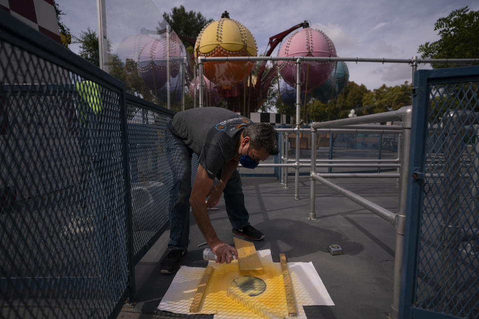 Allan Ansdell Jr., owner and president of Adventure City amusement park, spray paints social distancing dots on the streets of the amusement park ahead of its reopening in Anaheim, Calif., Wednesday, April 14, 2021. The family-run amusement park that had been shut since March last year because of the coronavirus pandemic reopened on April 16. "It's mixed emotions," he said, recalling the day he let go of most of his 150 employees, including his wife. Only a handful remained at the park. "Parks are seasonal. Sometimes you have a rainy month. We always have enough in our reserves for three or four months of who knows what. But nobody has a reserve for a year," Ansdell Jr. said. It's been hard for all of us. "I'm glad that we are getting through it. I'm glad we are reaching the end." (AP Photo/Jae C. Hong)