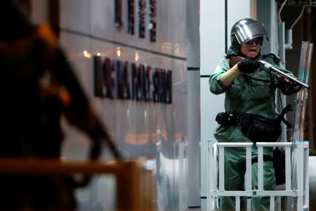 A riot police points beanbag shotgun at anti-extradition bill protesters as they surround Mongkok police station during a protest at Mong Kok in Hong Kong