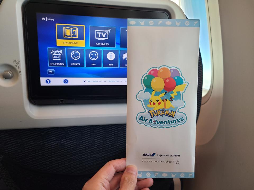 Envelope of Pokemon flight ticket being held in hand on plane 