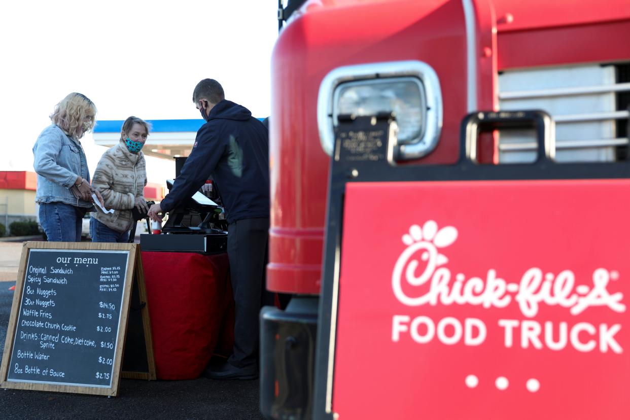 Kallie Schoenbachler, left, and grandmother Danile Kelly place their orders as customers wait in line to order at the Chick-Fil-A food truck in McMinnville, Oregon, Tuesday, Dec. 1, 2020. A Chick-fil-A food truck is now being proposed outside Lowe's Home Improvement in Rochester, New Hampshire.