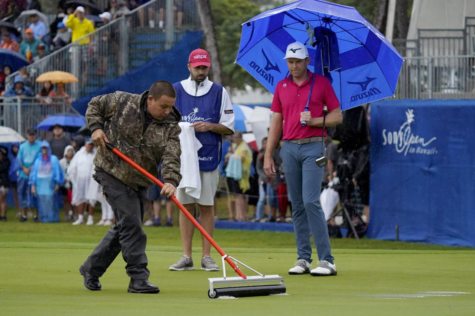 A course worker clears standing water off the 18th green before Bo Hoag putts during the final round of the Sony Open PGA Tour golf event, Sunday, Jan. 12, 2020, at Waialae Country Club in Honolulu. (AP Photo/Matt York)