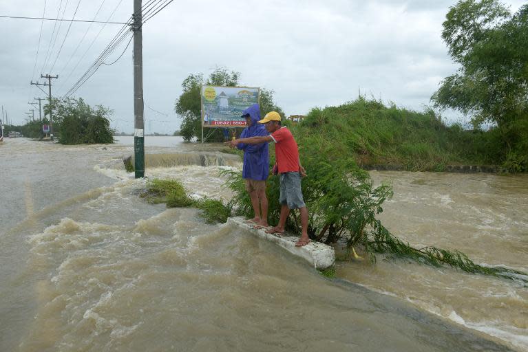 Stranded commuters stand in flood waters after Typhoon Nari pummelled the northern Philippines, on October 12, 2013