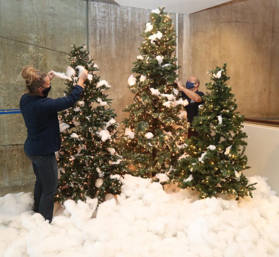 Margo Ohlson, left, the director of E.J. Thomas Hall and Dominic Cardarelli, senior account manager, decorate the lobby of the theater for the holidays on the University of Akron campus Friday in Akron.