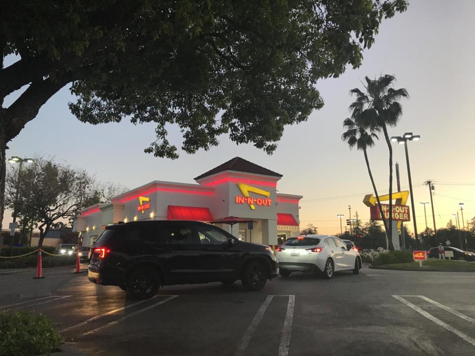 Cars wait in a drive-through lane at an In-N-Out location in Alhambra.